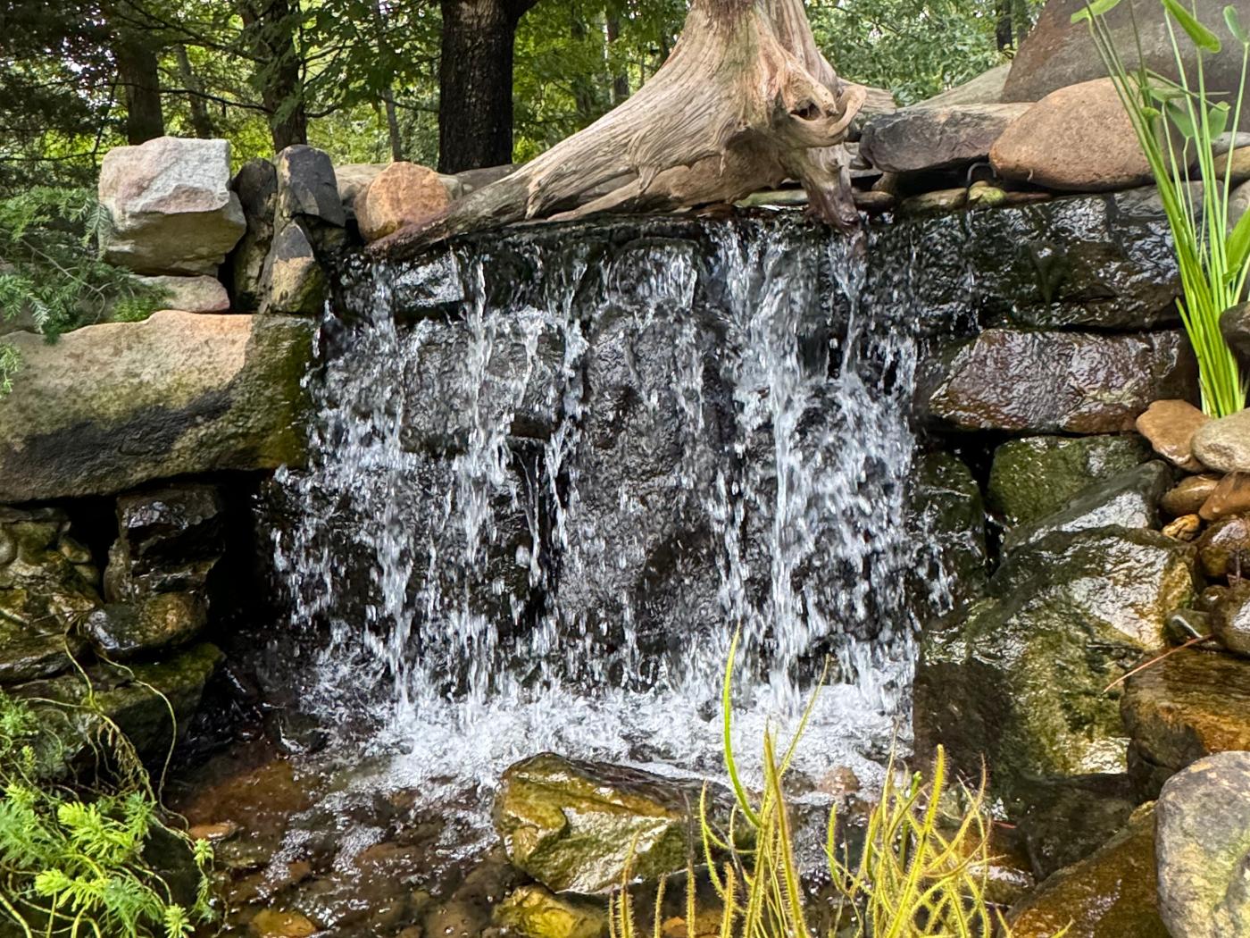 A waterfall that is in the middle of some rocks.