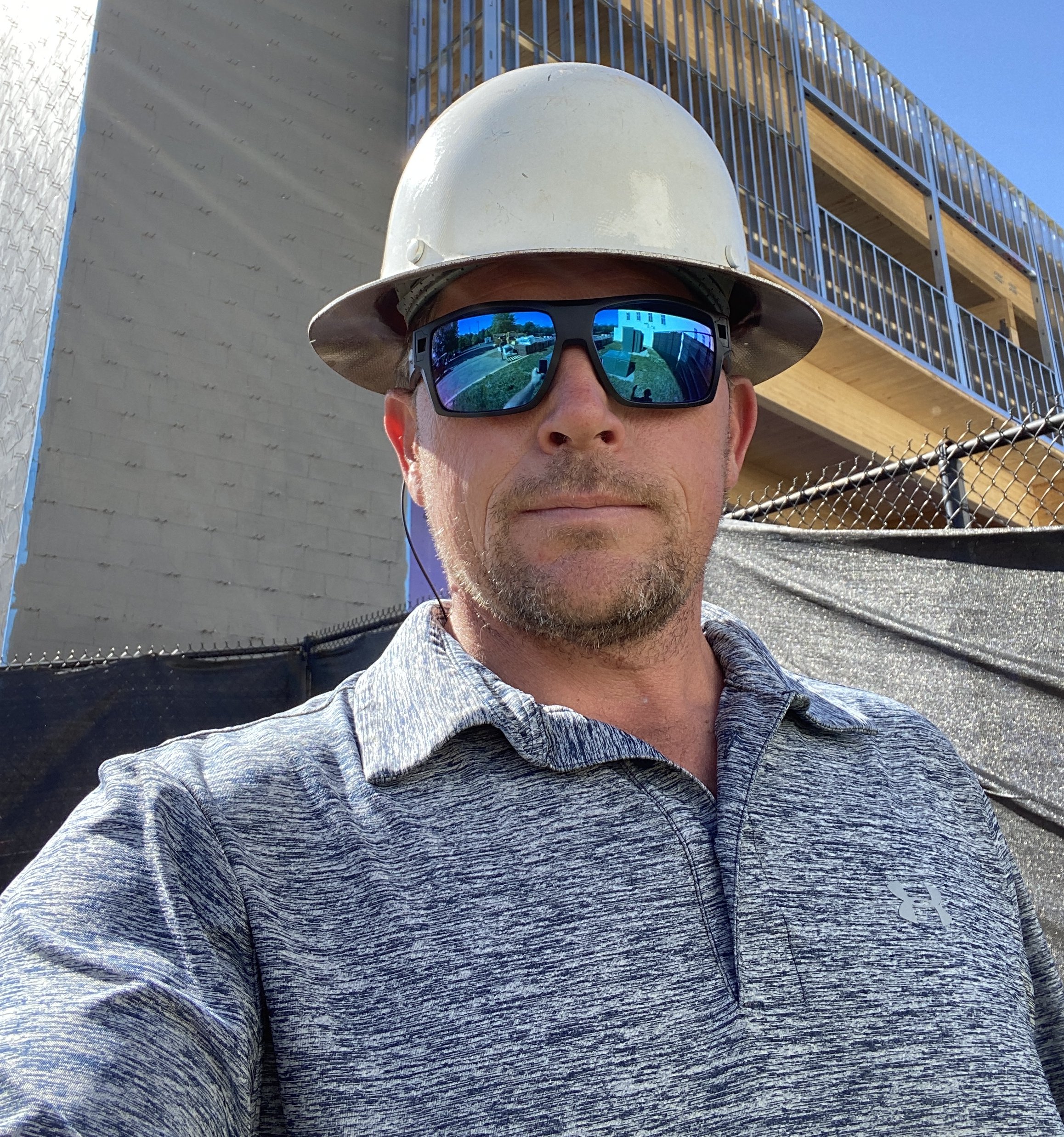 A man wearing a hard hat and sunglasses.