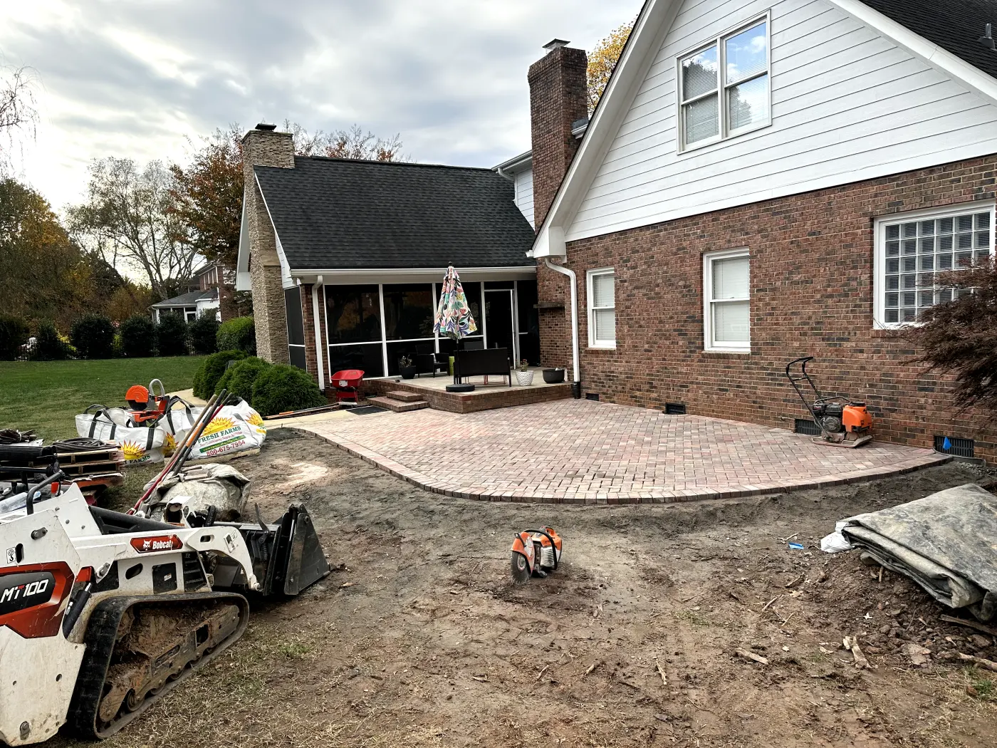 A brick patio being built in front of a house.