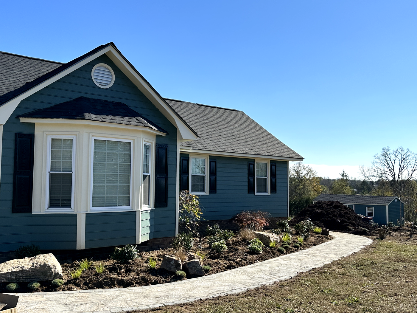 A blue house with a white trim and stone walkway.