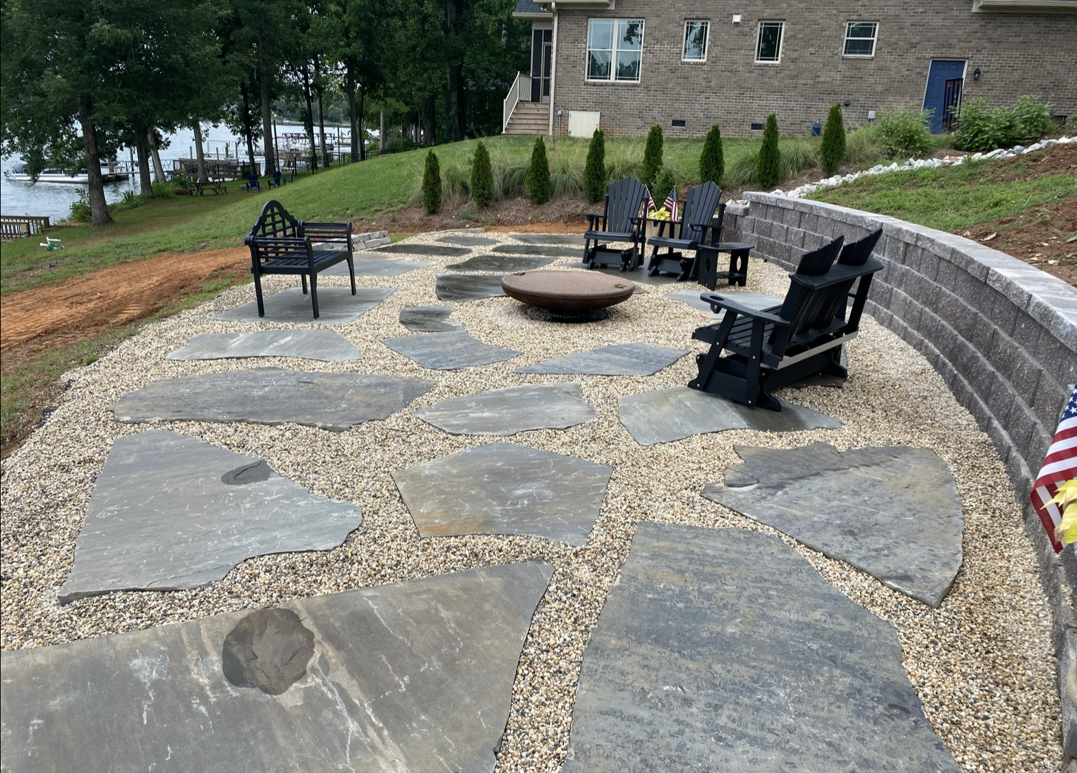 A patio with chairs and fire pit in the middle of it.