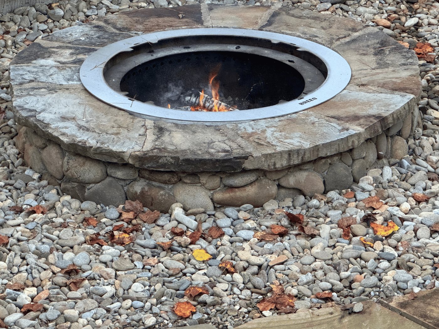 A fire pit with rocks and leaves around it