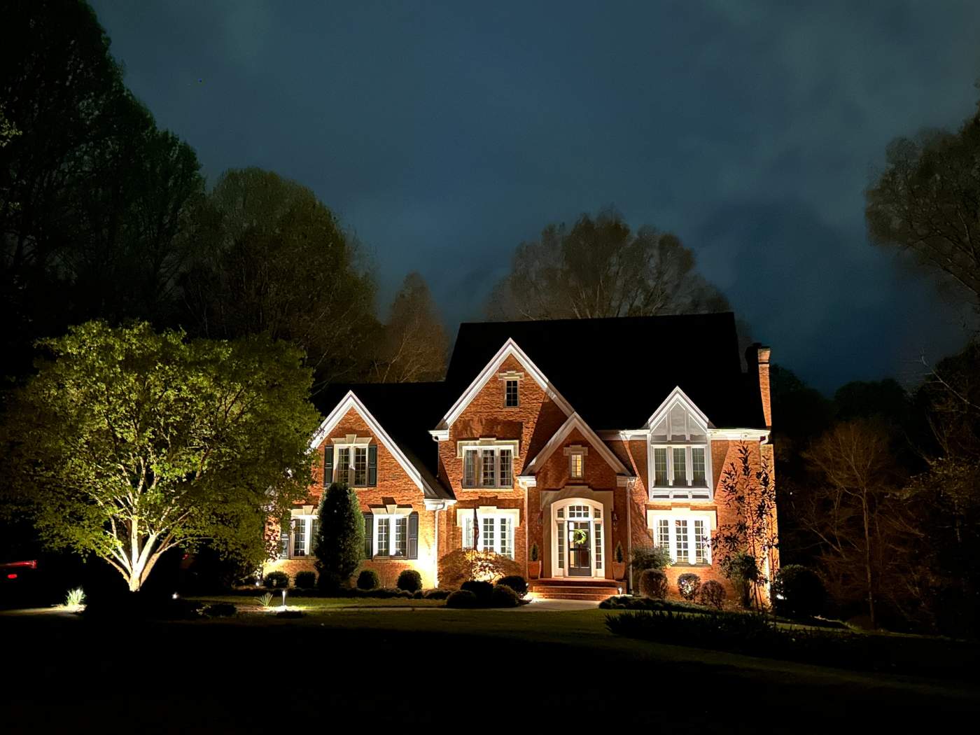 A large brick house lit up at night.