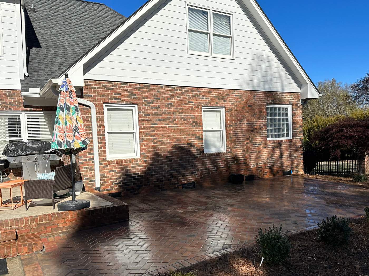 A brick house with a patio and umbrella.