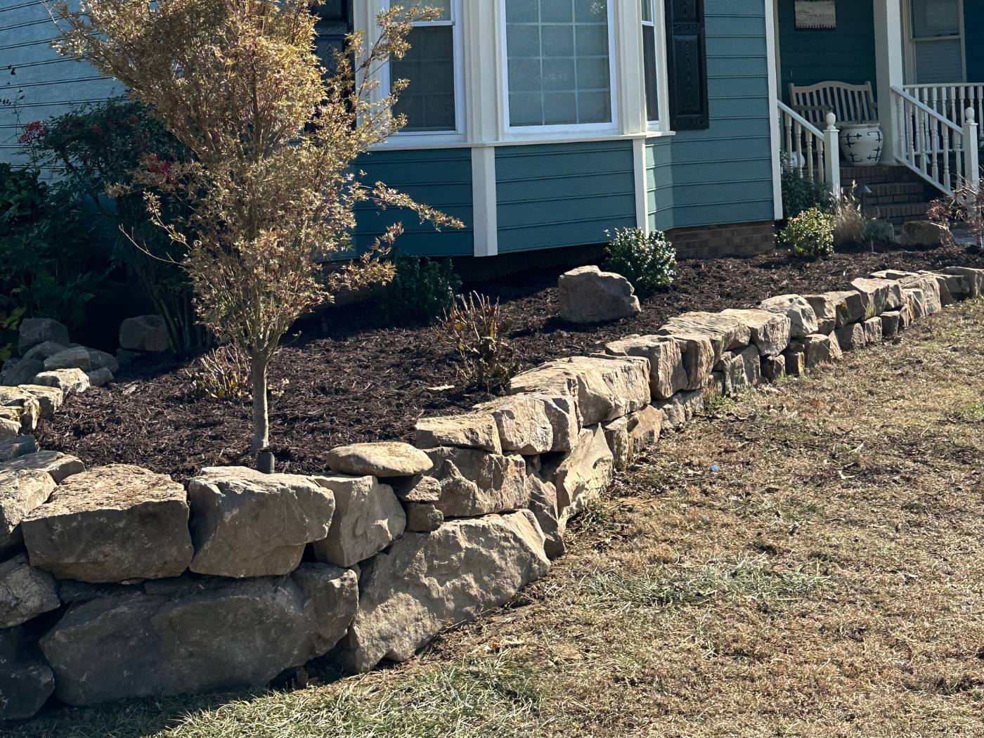 A house with a stone wall in the front yard.